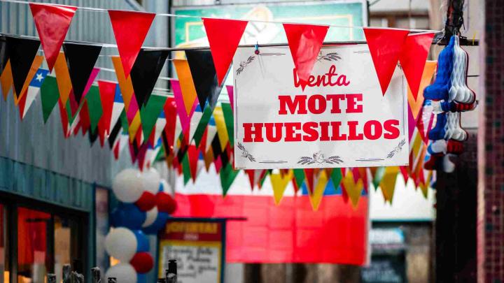 Muchos banderines de colores colgados y un letrero blanco con letras rojas que dice Mote con Huesillos